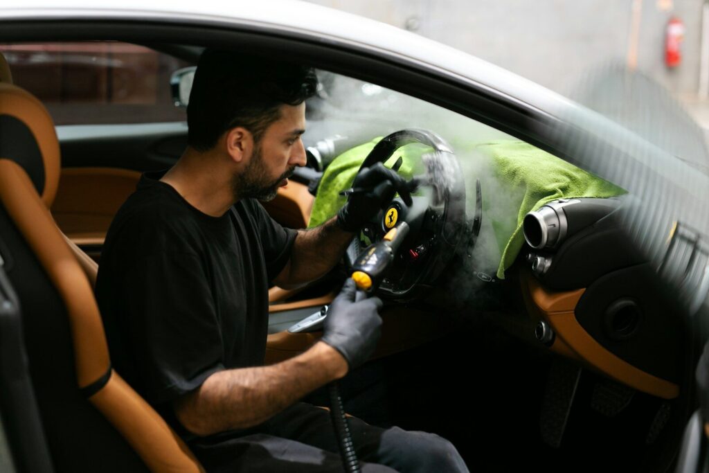 Man steam-cleans the interior of a car